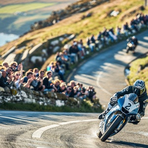 Op de afbeelding: Een motorcoureur scheurt door een scherpe bocht op een kronkelende weg. De coureur draagt een zwart-wit racepak en een helm. De weg is omzoomd door toeschouwers die de coureur aanmoedigen.