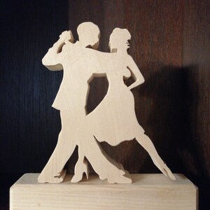 Könnte beinhalten: Eine Holzsilhouette eines tanzenden Paares, der Mann im Anzug und die Frau im Kleid, stehend auf einem Holzsockel.