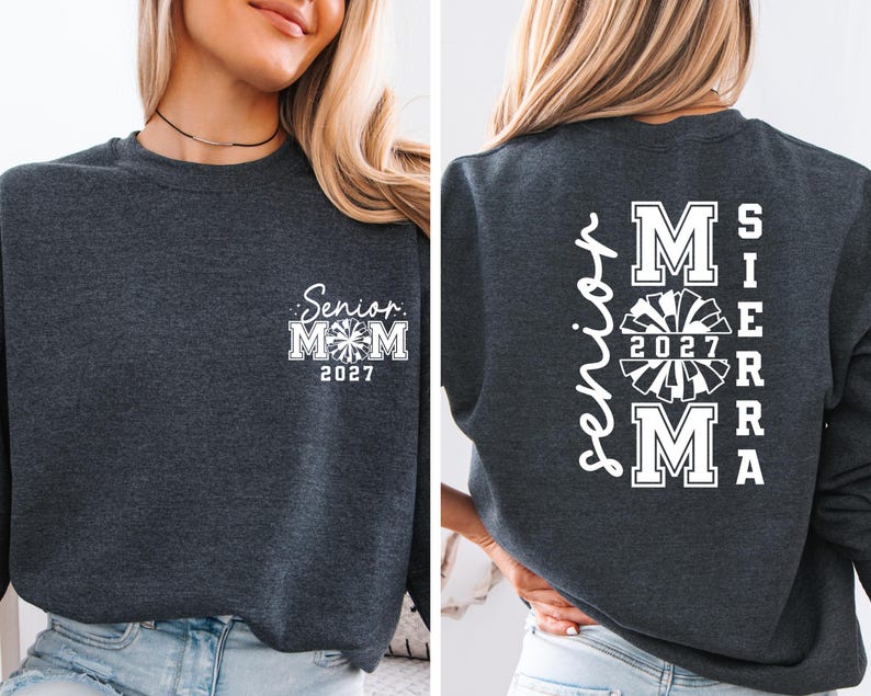 May include: Dark gray sweatshirt with white text. The front features "Senior Mom 2027" with a pom-pom graphic. The back displays "Mom Sierra 2027" in a vertical and stacked design, also with a pom-pom graphic.