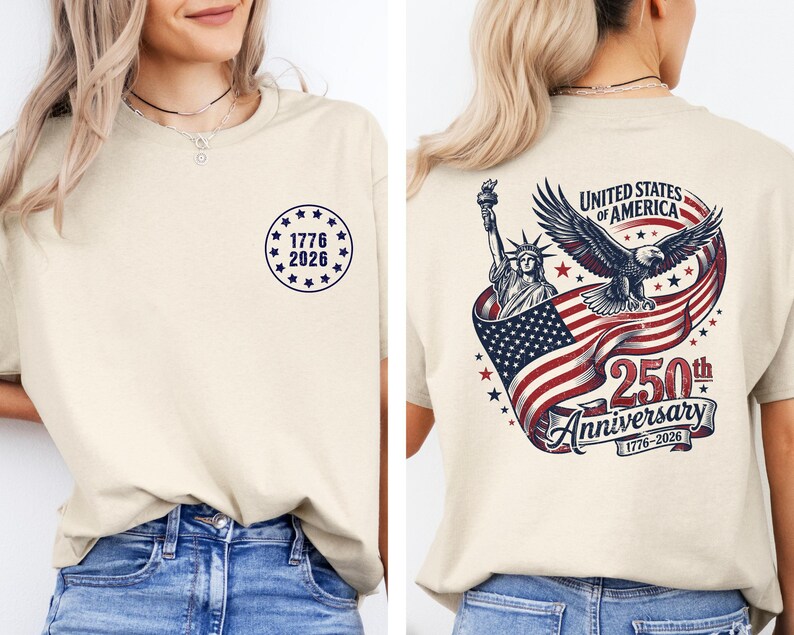Pode incluir: Camiseta creme com design patri&oacute;tico. A frente exibe um emblema circular com o texto "1776 2026". A parte de tr&aacute;s apresenta a Est&aacute;tua da Liberdade, uma &aacute;guia e a bandeira americana, com o texto "250th Anniversary".