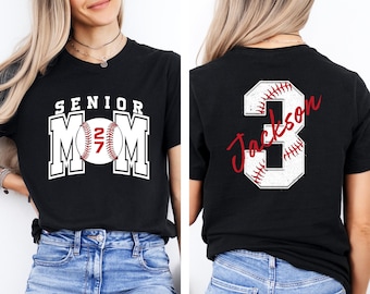 May include: A black t-shirt featuring a front graphic with the text SENIOR MOM and a baseball with the number 27. The back graphic displays a large number 3 with baseball stitching and the name Jackson written in red script across the number.