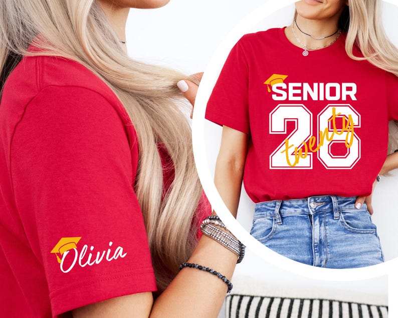 May include: Red t-shirt with the text "SENIOR 26 Twenty" in white and yellow, and a graduation cap graphic. The sleeve features the name "Olivia" in white script with a graduation cap icon. The shirt is paired with blue jeans.