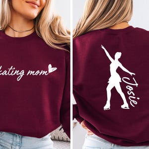 May include: Burgundy sweatshirt with the text "skating mom" and a heart on the front. The back of the sweatshirt has a white silhouette of a figure skater with the name "Josie" written next to it.