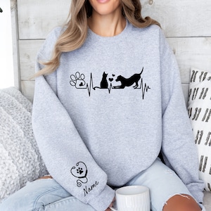 May include: Gray sweatshirt with a black paw print, heartbeat, cat, and dog graphic. The text "Name" is on the sleeve with a stethoscope and paw print graphic.