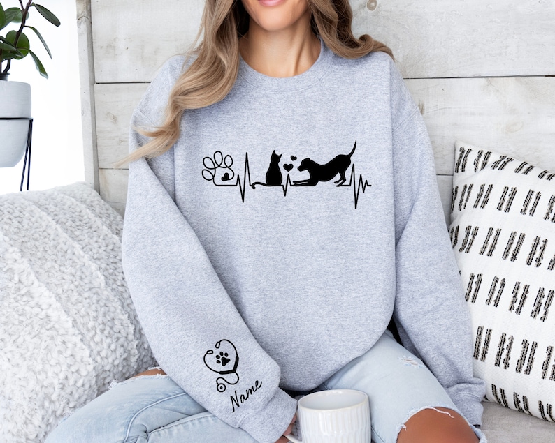 May include: Gray sweatshirt with a black paw print, heartbeat, cat, and dog graphic. The text "Name" is on the sleeve with a stethoscope and paw print graphic.