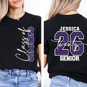 May include: Black t-shirt with "Class of 2026" in white script and purple block letters. The back of the shirt features the name "Jessica", the number "26", and the word "Senior" in white and purple.