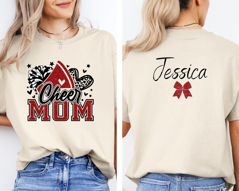Puede incluir: Una camiseta beige con un gr&aacute;fico rojo, negro y blanco que dice "Cheer Mom" y un lazo rojo en la espalda con el nombre "Jessica".