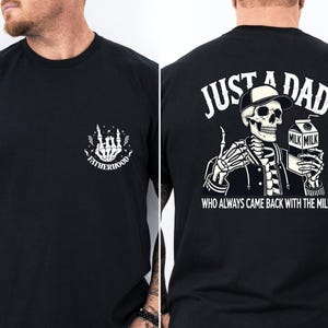 May include: Black t-shirt with a white graphic on the front of a skeleton hand with the word "FATHERHOOD". The back of the shirt features a skeleton wearing a hat and jacket, holding a milk carton, with the text "JUST A DAD WHO ALWAYS CAME BACK WITH THE MILK".