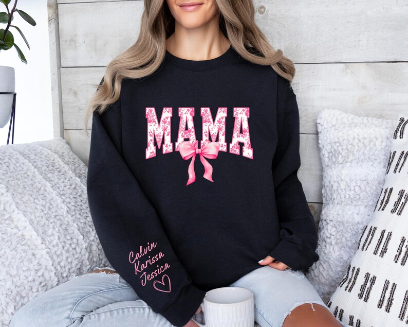 May include: Black sweatshirt with the word "MAMA" in pink and white letters with a pink bow. The sweatshirt has the names "Calvin, Karissa, Jessica" written on the sleeve.