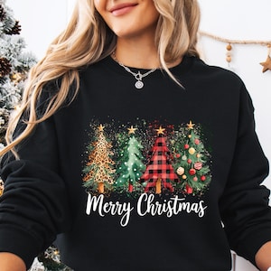 May include: Black sweatshirt featuring a festive design with four Christmas trees. The trees include a leopard print, green, red plaid, and decorated tree. The words "Merry Christmas" are written in white script below the trees.
