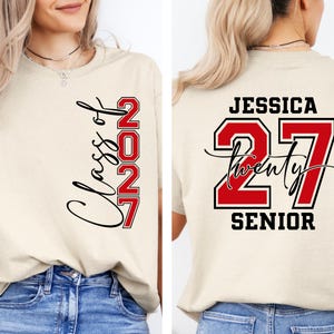 May include: Beige t-shirt with "Class of 2027" and "27" in red and black. The back of the shirt features the name "Jessica", the number "27", and the word "Senior". A casual tee for graduation.