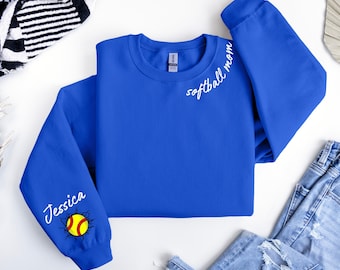 May include: Royal blue sweatshirt with the words "softball mom" in white script on the upper right sleeve. The left sleeve features the name "Jessica" and a softball design. The softball is yellow and red with a cracked design.