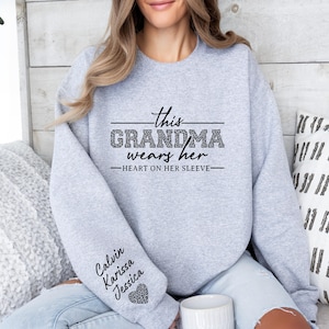 May include: Gray sweatshirt with the text "This Grandma wears her heart on her sleeve" and the names "Calvin, Karissa, Jessica" on the sleeve.
