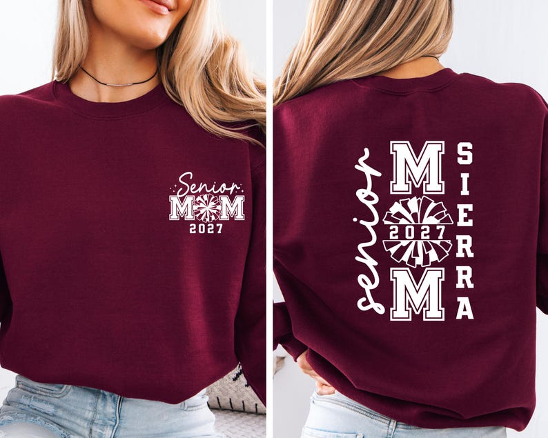 May include: A maroon sweatshirt with white text. The front features "Senior Mom 2027" with a cheerleader graphic. The back displays "Senior Mom" vertically, with "Sierra" and "2027" and a cheerleader graphic.