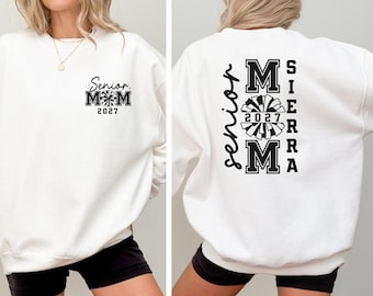 May include: White sweatshirt with black text and graphics. The front features "Senior Mom 2027" with a pom-pom design. The back displays "Senior" vertically, and "Sierra Mom 2027" with a pom-pom graphic.