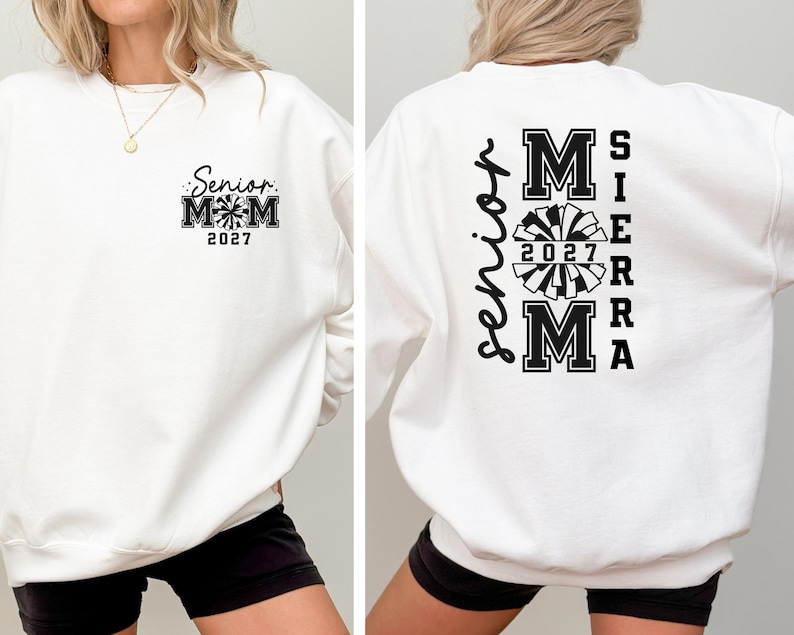 May include: White sweatshirt with black text and graphics. The front features "Senior Mom 2027" with a pom-pom design. The back displays "Senior" vertically, and "Sierra Mom 2027" with a pom-pom graphic.