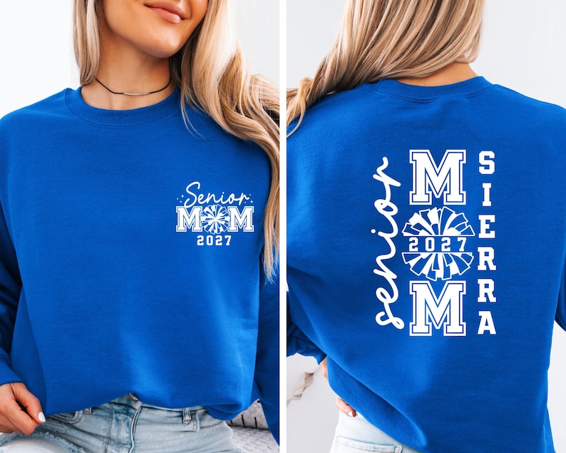 May include: Royal blue sweatshirt with white text. The front features "Senior Mom 2027" with a cheerleader graphic. The back displays "Senior Mom 2027 SIERRA" in a vertical arrangement with a cheerleader graphic.