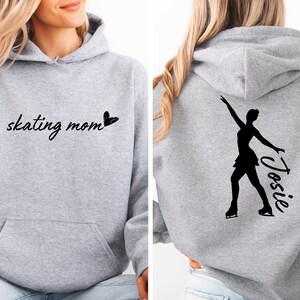 May include: Gray hoodie with the text "skating mom" and a heart on the front. The back of the hoodie has a silhouette of a figure skater with the name "Josie" written next to it.