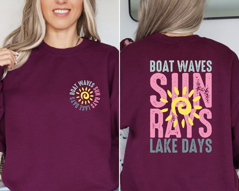 May include: Burgundy sweatshirt with a sun graphic and the text "Boat Waves Sun Rays Lake Days" in pink, yellow, and blue.