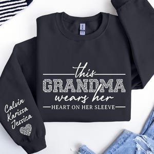 May include: Black sweatshirt with the text "This Grandma wears her heart on her sleeve" and the names "Calvin, Karissa, Jessica" on the sleeve.