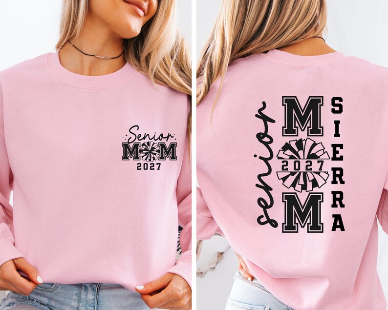 May include: A light pink sweatshirt with the text "Senior Mom 2027" and a cheerleading graphic on the front. The back of the sweatshirt has the name "Sierra" and "Mom 2027" with a cheerleading graphic.