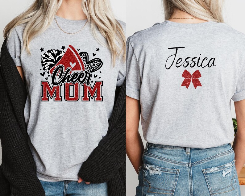 Puede incluir: Camiseta gris con un dise&ntilde;o de mam&aacute; animadora en rojo, blanco y negro en la parte delantera y un lazo rojo y el nombre Jessica en la parte posterior.