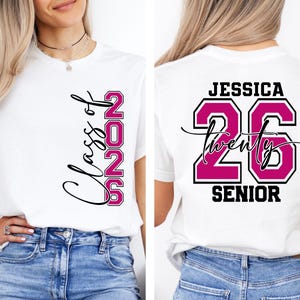 May include: White t-shirt with "Class of 2026" in black script and pink block letters. The back of the shirt features the name "Jessica", the number "26", and the word "Senior" in black and pink.