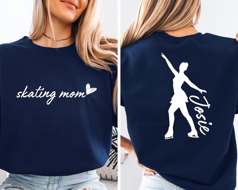 May include: Navy blue sweatshirt with white text that says "skating mom" and a heart. The back of the sweatshirt has a white silhouette of a figure skater with the name "Josie" written next to it.