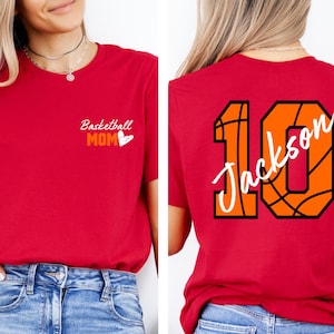 Peut inclure: T-shirt rouge avec le texte "Basketball Mom" et un c&oelig;ur sur le devant. Le dos du t-shirt pr&eacute;sente un motif de basket-ball avec le num&eacute;ro 10 et le nom "Jackson" &eacute;crit dessus.