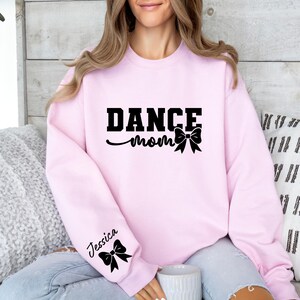 Pu&ograve; includere: Felpa rosa con la scritta "Dance Mom" e un fiocco nero. La felpa ha un fiocco nero sulla manica sinistra con la scritta "Jessica".