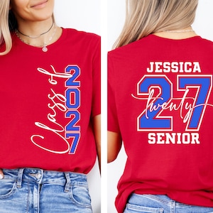 May include: Red t-shirts with white and blue text. One shirt says "Class of 2027" on the front. The other shirt has "Jessica 27 Twenty Senior" on the back. The shirts are worn by a person.