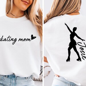 May include: White sweatshirt with the text "skating mom" and a heart on the front. The back of the sweatshirt has a silhouette of a figure skater with the name "Josie" written next to it.