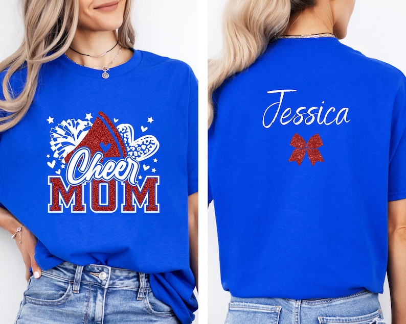 Puede incluir: Camiseta azul con un dise&ntilde;o de porrista rojo, blanco y azul que dice "Cheer Mom". La parte posterior de la camiseta tiene un lazo rojo y el nombre "Jessica" escrito en blanco.
