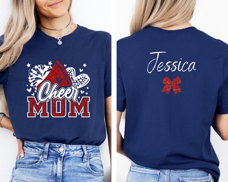 Puede incluir: Camiseta azul marino con un dise&ntilde;o de porrista rojo y blanco y el texto "Cheer Mom". La parte posterior de la camiseta tiene el nombre "Jessica" en escritura cursiva blanca y un lazo rojo de brillantina.