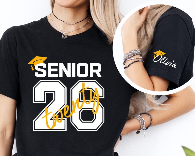 May include: Black t-shirt with "SENIOR 20" in white and yellow lettering, featuring a graduation cap graphic. The sleeve has a graduation cap graphic and the name "Olivia" in white.