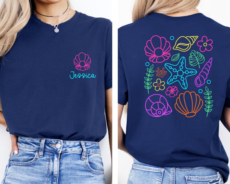 May include: Navy blue t-shirt with a seashell design and the name "Jessica" in teal. The back of the shirt features a colorful neon design of seashells, starfish, and flowers. A casual, beach-themed tee.