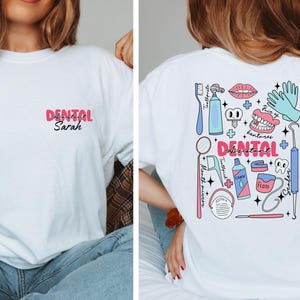 May include: White t-shirt with a pink and black design that says "Dental Assistant Sarah" on the front and a colourful illustration of dental tools and equipment on the back.