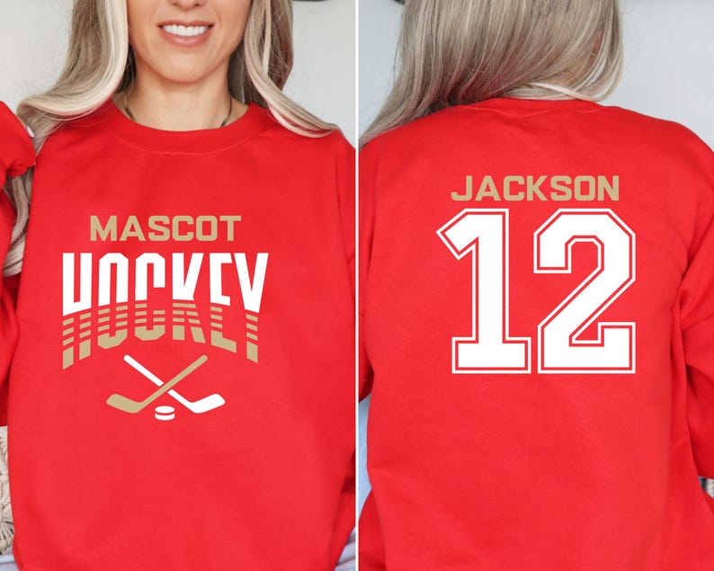 K&ouml;nnte beinhalten: Roter Pullover mit einem gold-wei&szlig;en Hockey-Design auf der Vorderseite. Die R&uuml;ckseite des Pullovers hat eine wei&szlig;e Nummer 12 mit dem Namen "JACKSON" dar&uuml;ber.