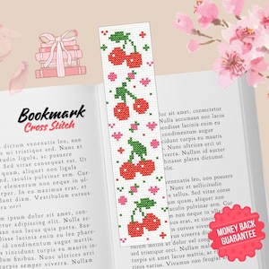 May include: A cross-stitch bookmark with a design of red cherries, green stems, and pink hearts. The bookmark is on an open book. The words "Bookmark Cross Stitch" are visible at the top of the image.