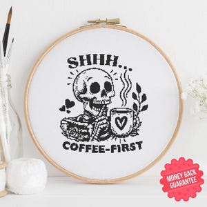 Könnte beinhalten: Schwarzweißes Kreuzstichmuster mit einem Skelett, das eine Kaffeetasse mit dem Text "Shhh... Coffee-First" hält.