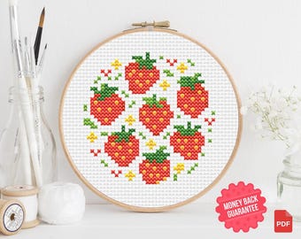 May include: A cross-stitch embroidery hoop featuring a pattern of red strawberries with green leaves and yellow accents. The design is set against a white background, framed by a wooden hoop. The image includes a "Money Back Guarantee" sticker and a PDF icon.