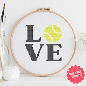 May include: A cross-stitch pattern featuring the word "LOVE" with a yellow tennis ball in the "O". The pattern is displayed in a wooden embroidery hoop.