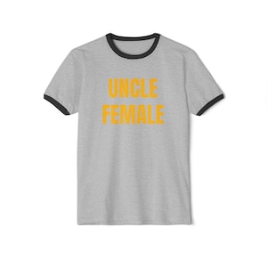 May include: A grey t-shirt with a black ringer and the words "UNCLE FEMALE" printed in orange.