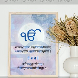 Puede incluir: Una impresión enmarcada con un fondo de acuarela azul y blanco. La impresión presenta un símbolo azul con el texto "ੴ" en el centro. Debajo del símbolo hay un texto en otro idioma. El texto dice "ਸਤਿਨਾਮੁਕਰਤਾਪੁਰਖੁਨਿਰਭਉਨਿਰਵੈਰੁ ਅਕਾਲਮੂਰਤਿਅਜੂਨੀਸੈਭੰਗੁਰਪ੍ਰਸਾਦਿ॥ ॥ਜਪੁ॥ ਆਦਿਸਚੁਜੁਗਾਦਿਸਚੁ॥ ਹੈਭੀਸਚੁਨਾਨਕਹੋਸੀਭੀਸਚੁ॥੧॥"