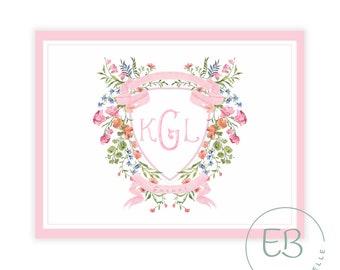May include: A pink framed print featuring a floral crest design. The crest includes a pink ribbon banner, the initials "KGL", and the name "Garner". The crest is surrounded by a wreath of pink, blue, and orange flowers and green leaves.
