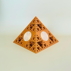Puede incluir: Una pirámide geométrica tridimensional de color dorado con un patrón fractal. La pirámide tiene dos círculos blancos con un diseño en espiral en los lados.