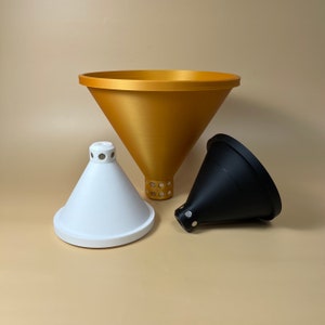 Op de afbeelding: Drie trechters in verschillende maten en kleuren. Een grote gouden trechter, een middelgrote witte trechter en een kleine zwarte trechter.