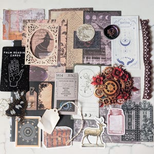 May include: A collection of assorted paper ephemera including tarot cards, a palm reading card, a vintage ticket labeled 1654 JIN3, a deer illustration, a treasure chest, a mason jar, a gate, and a decorative frame featuring a cat silhouette.