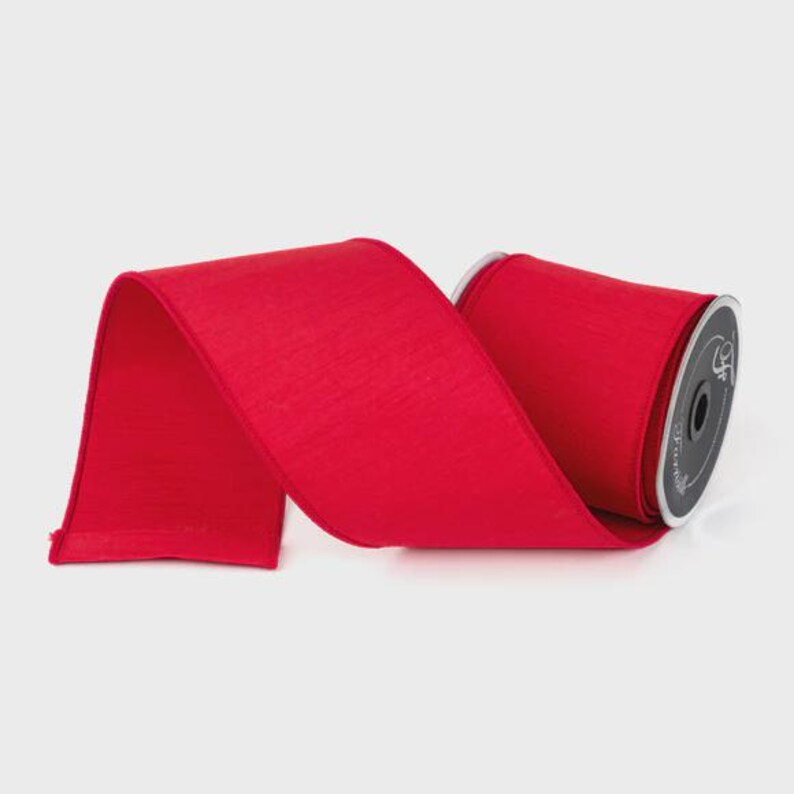 Puede incluir: Un rollo de cinta roja brillante con una superficie texturizada. La cinta ancha parece estar hecha de un material similar al sat&eacute;n. El carrete es visible en el lado derecho, con una etiqueta negra y plateada.
