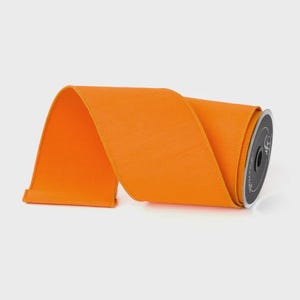 Puede incluir: Un rollo de cinta naranja brillante. La cinta es de color liso y tiene un aspecto texturizado. La bobina es negra con texto blanco. Esta cinta es adecuada para manualidades, envolver regalos y decoraciones.